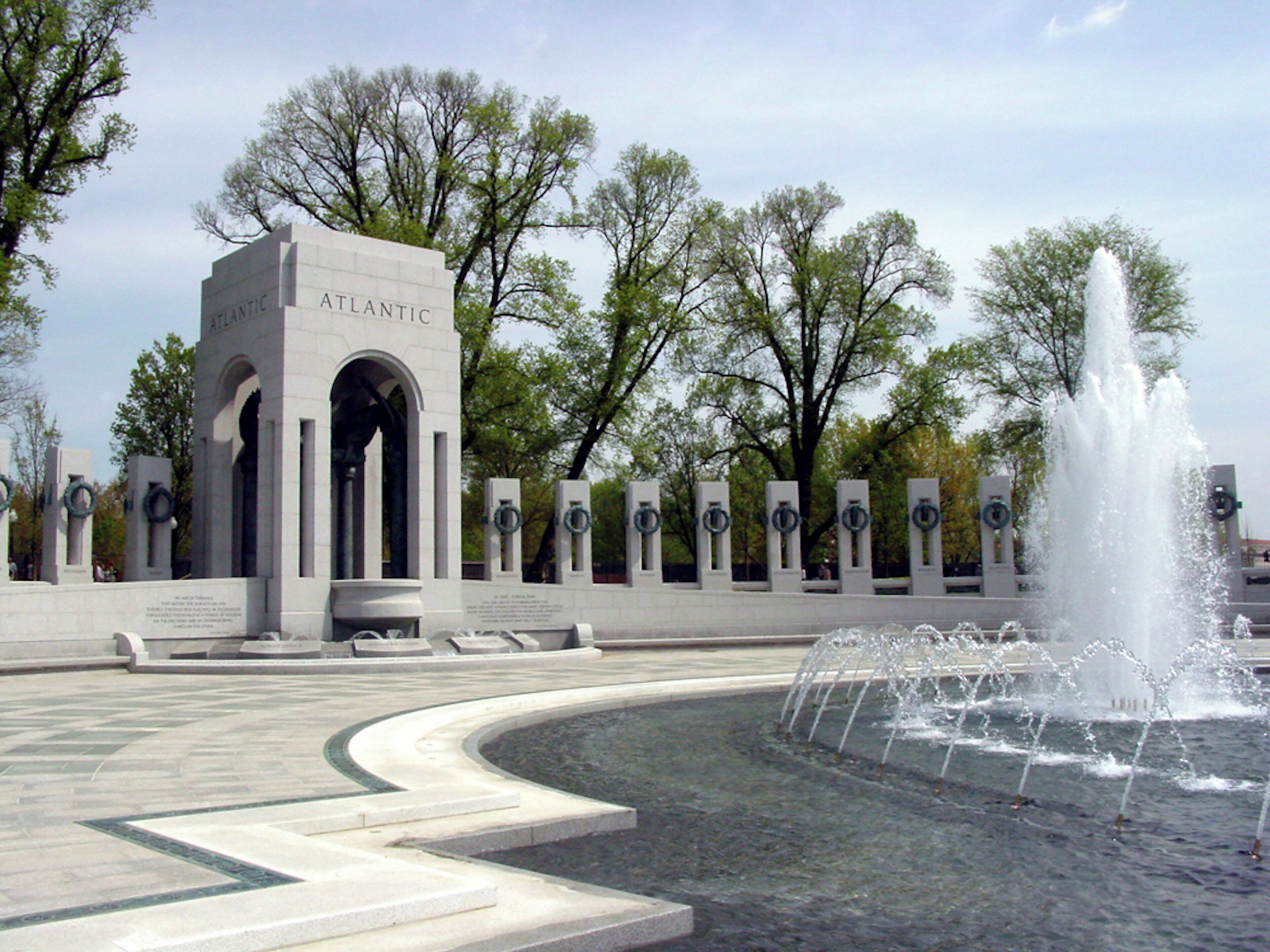 A memorial with a fountain and trees in the background.