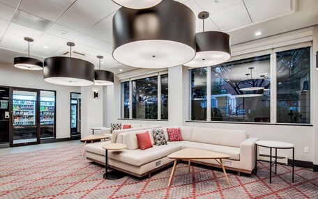 A modern hotel lobby with a white sofa, round tables, and pendant lighting.