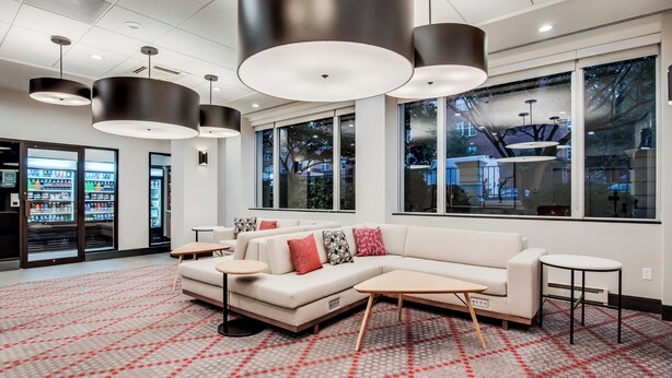 A modern hotel lobby with a white sofa, round tables, and pendant lighting. - Holiday Inn Washington-Central/White House by IHG (Washington)
