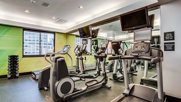 A gym with treadmills, elliptical machines, and a weight rack.