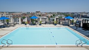 A rectangular pool with a diving board, surrounded by lounge chairs and umbrellas. - Holiday Inn Washington-Central/White House by IHG (Washington)