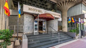 Exterior del Hotel Concorde, con fachada de baldosas, una entrada central y varias banderas.