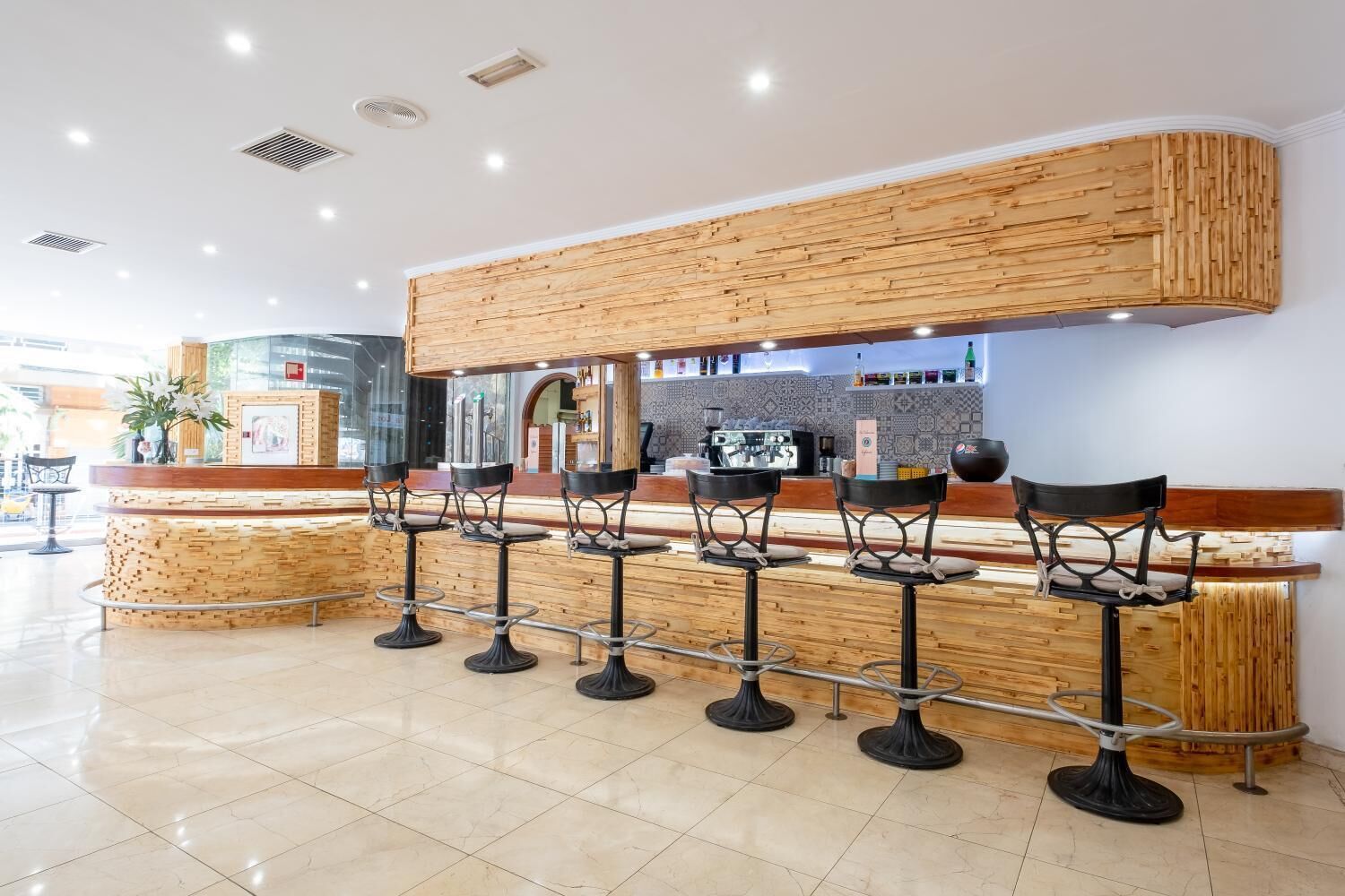 A bar area with wooden bar counters and black stools.