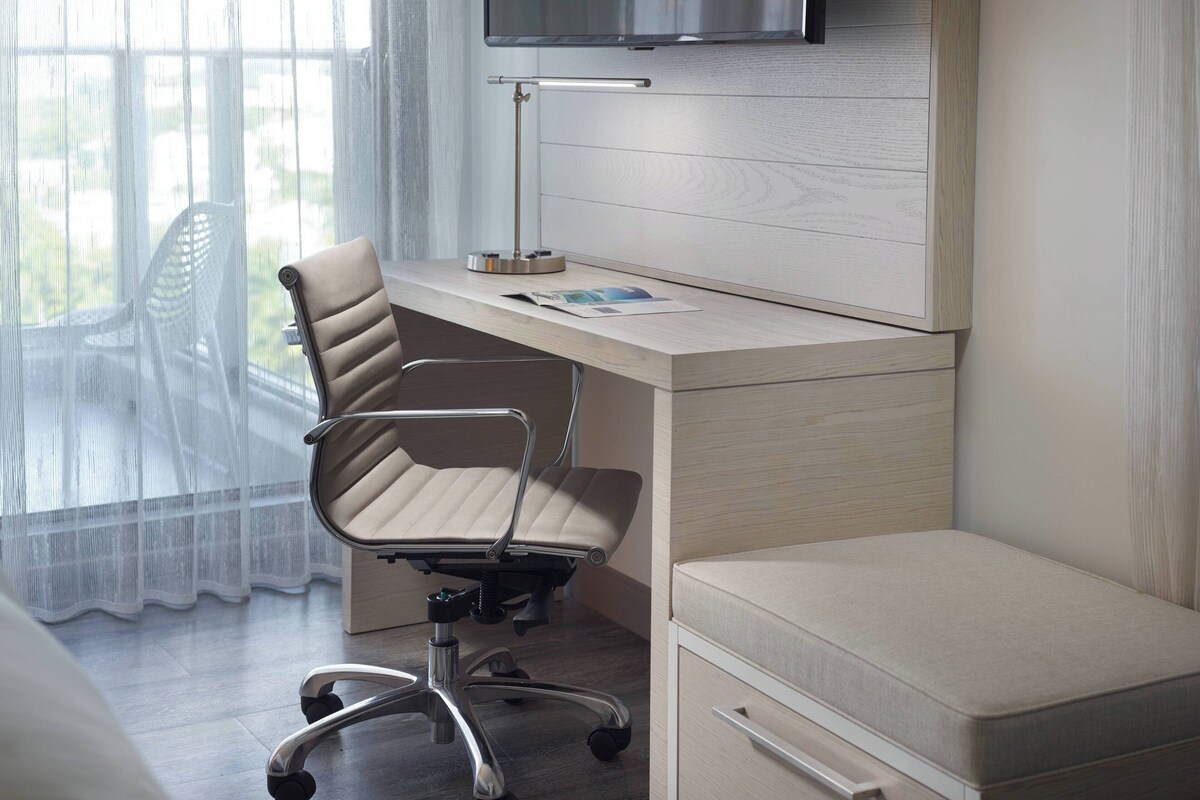 A modern office space with a desk, chair, and a small bed.