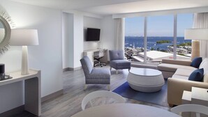 A modern hotel room with a large window offering a view of the marina and cityscape.