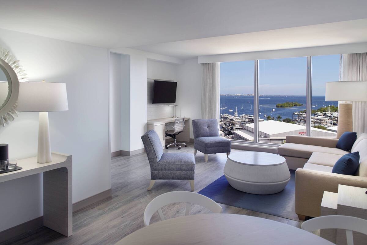 A modern hotel room with a large window offering a view of the marina and cityscape.