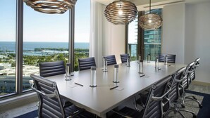 A conference room with a large table, black leather chairs, and modern pendant lights.