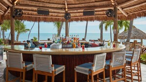 A bar area with a thatched roof, wooden chairs, and a view of the ocean. - Cheeca Lodge & Spa (Islamorada)