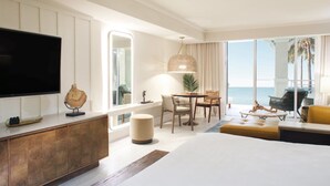 A hotel room with a large bed, a television, a dining area with chairs, a table, and a view of the ocean. - Cheeca Lodge & Spa (Islamorada)