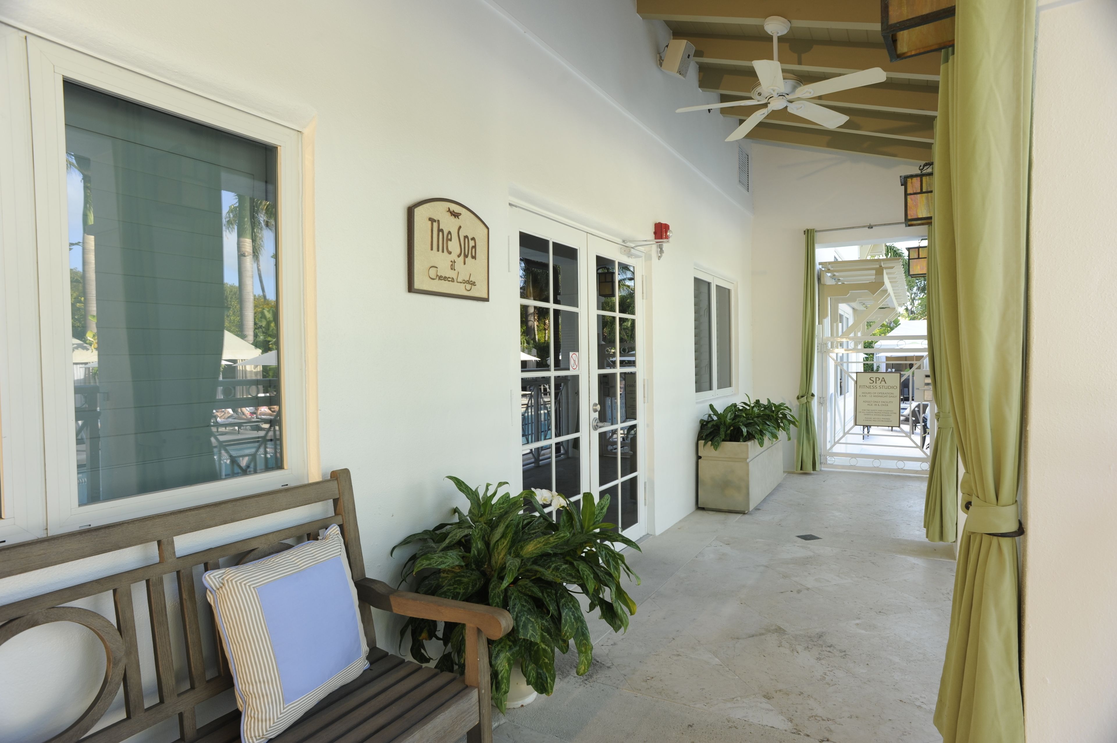 A covered outdoor area with a bench, potted plants, and a sign for 'The Spa at Casa Loma'.