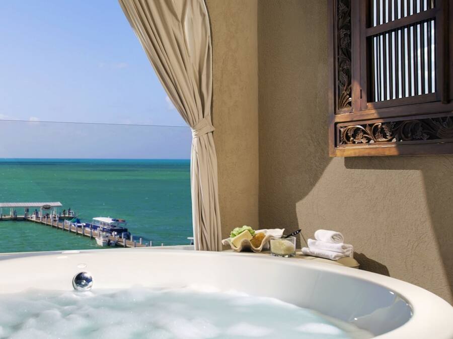 A bathroom with a large bathtub, a view of the sea, and a pier with boats.