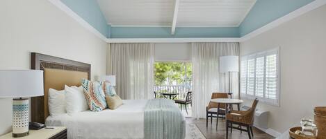 A hotel room with a bed, bedside table, lamp, and a view of the outdoors.