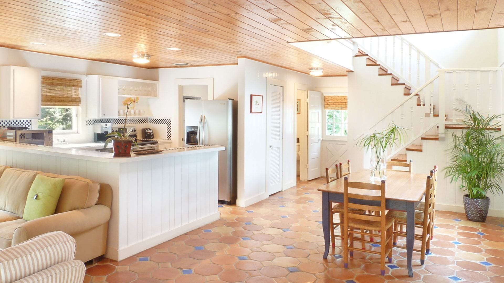 A spacious living area with a kitchen, a dining table with chairs, a sofa, and a staircase.