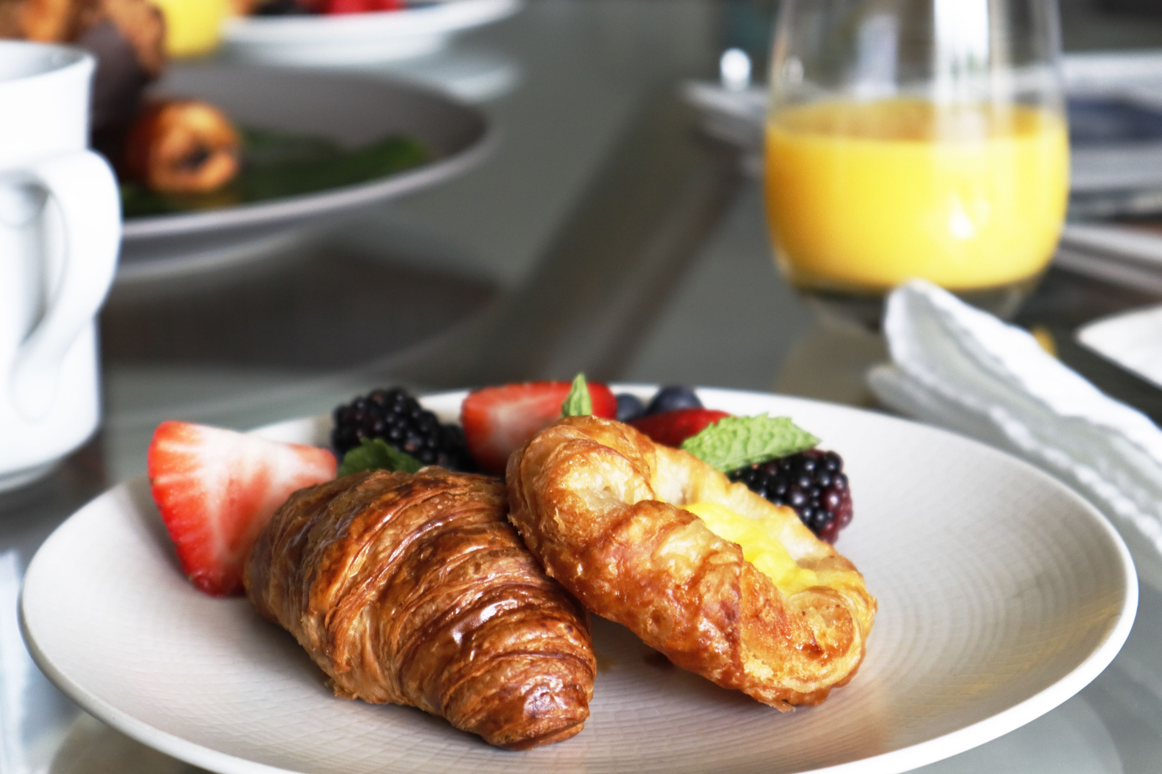 A breakfast plate with croissants and fresh fruit.