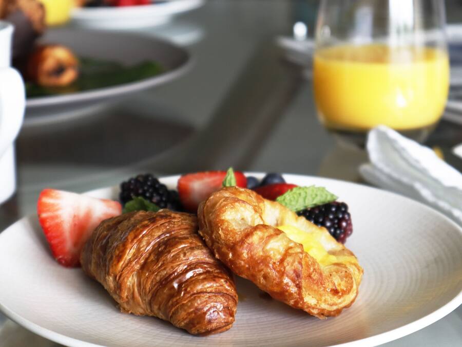 A breakfast plate with croissants and fresh fruit.