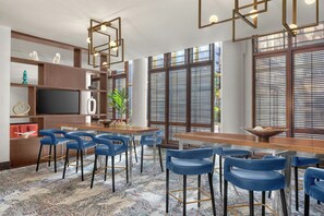 Un espace bar moderne avec des tabourets de bar bleus, un comptoir en bois et un téléviseur.