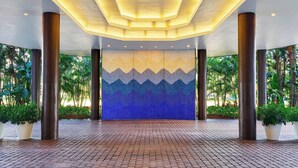 A spacious lobby with a tiled floor, large pillars, and a ceiling with recessed lighting.