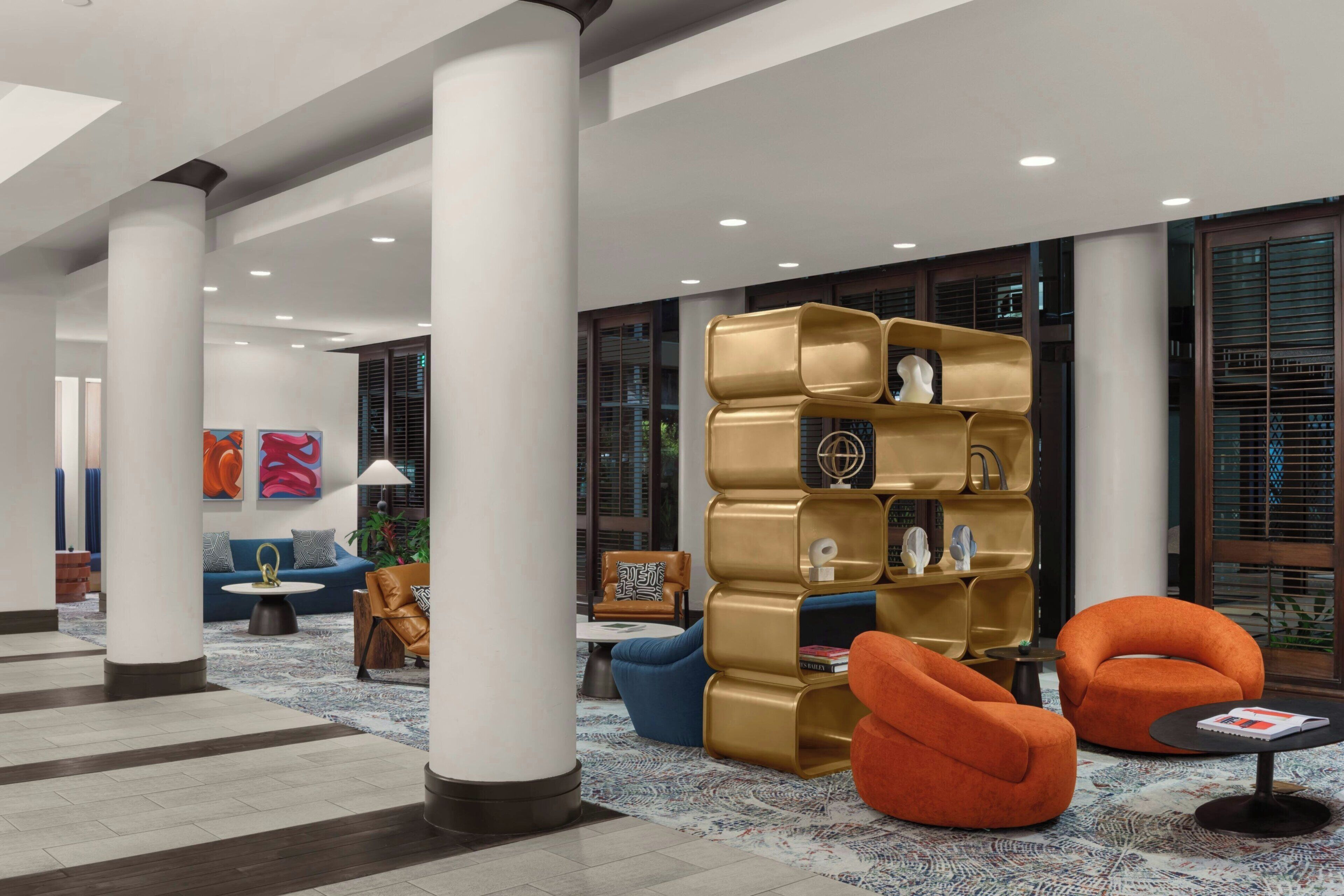 Een moderne lobby met een centraal zitgedeelte, een salontafel en een boekenkast.