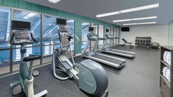A modern gym with treadmills, an elliptical, and a rowing machine.