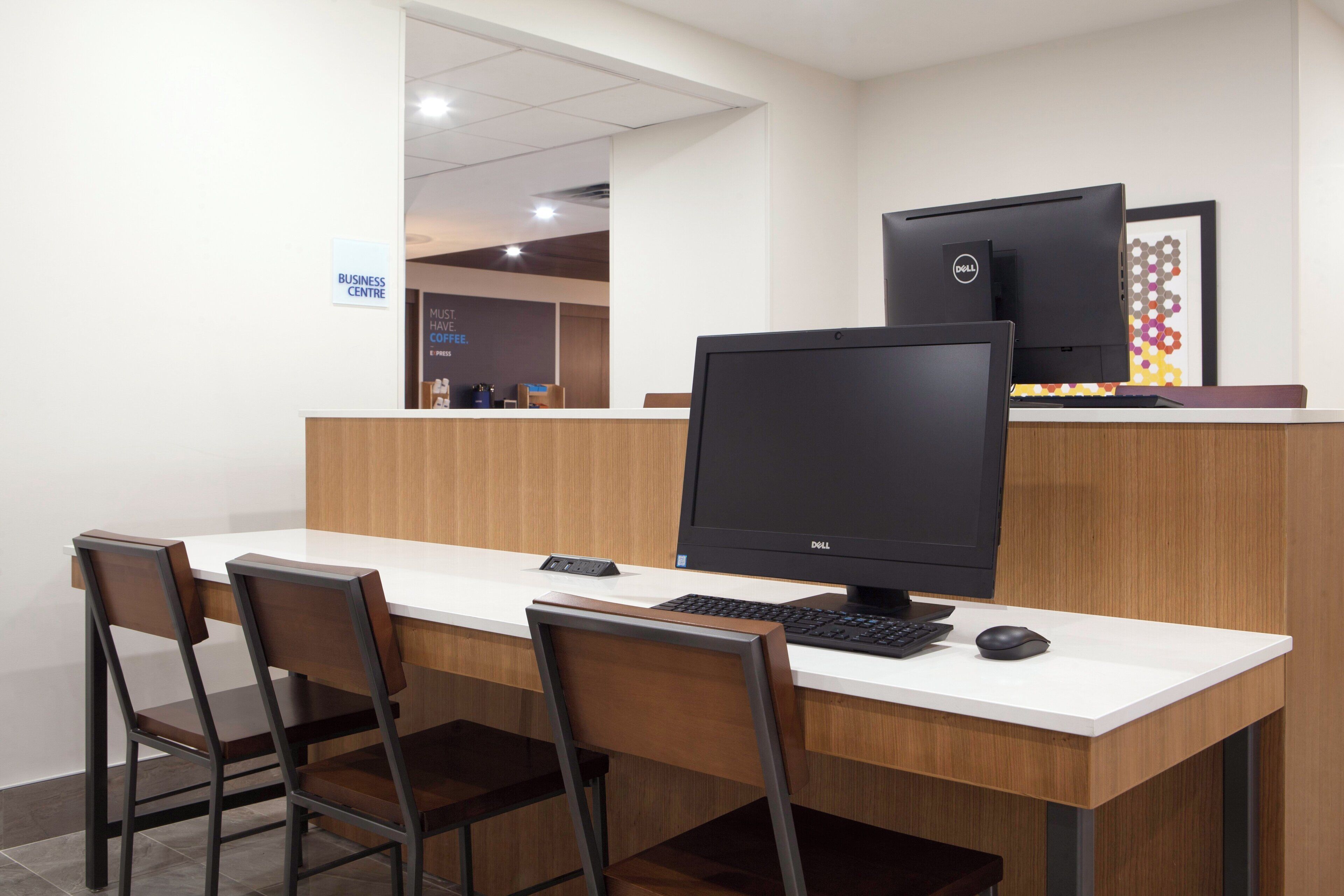 A business center with a desk, chairs, a computer, and a Dell monitor.