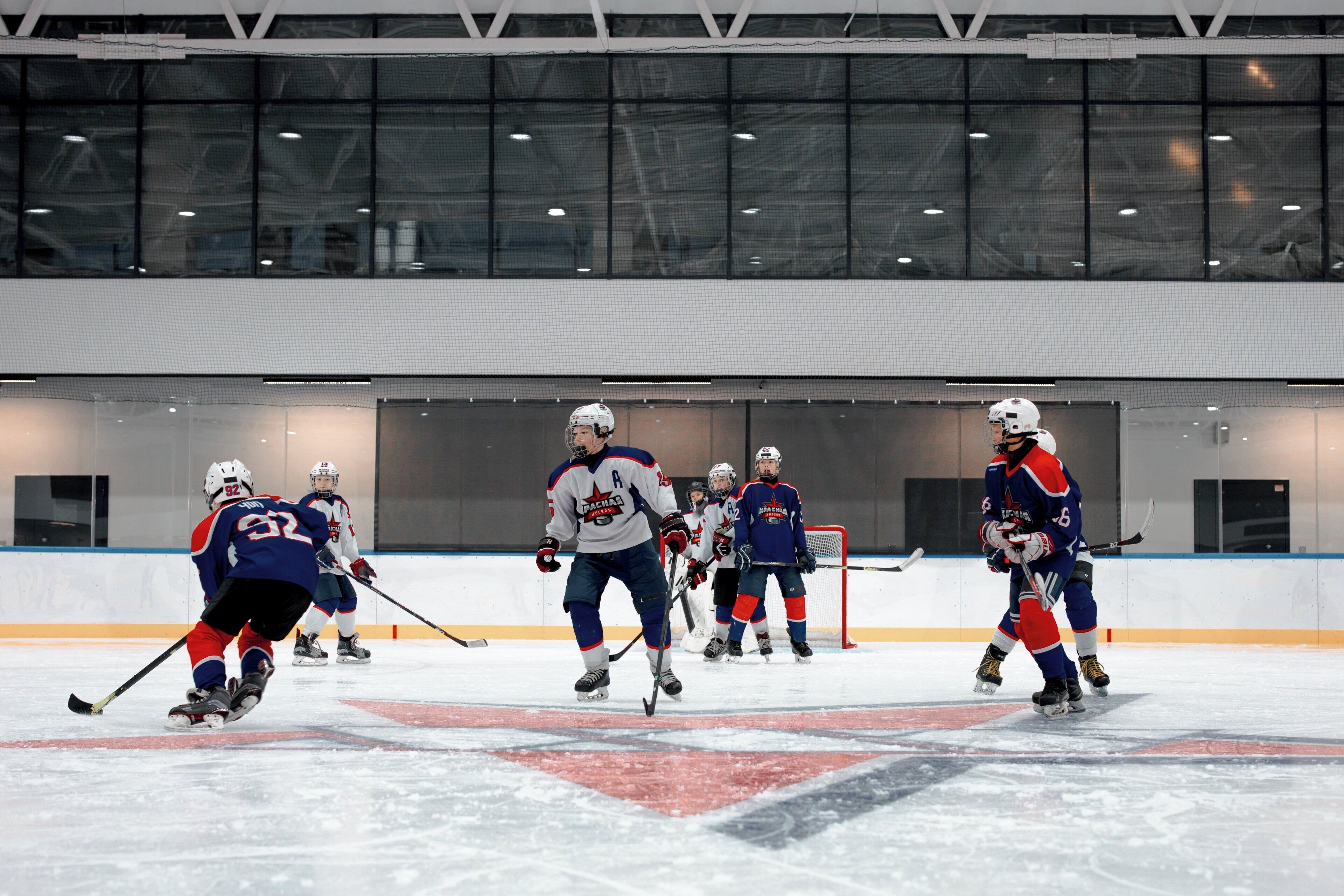 Une patinoire intérieure où se pratique le hockey sur glace, avec des joueurs portant des maillots bleus et blancs.