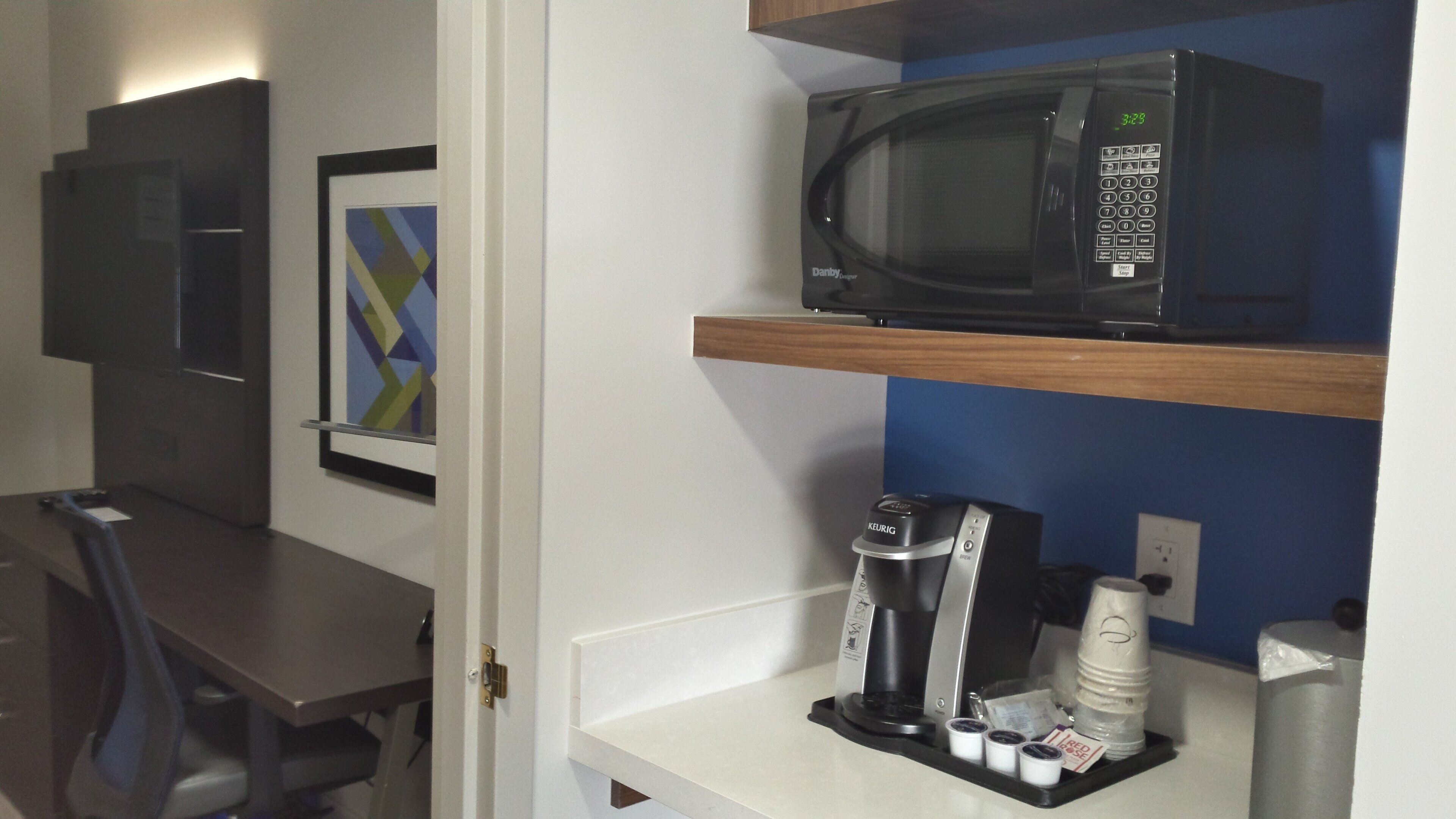 Una kitchenette equipada con microondas, cafetera y dispensador de café.