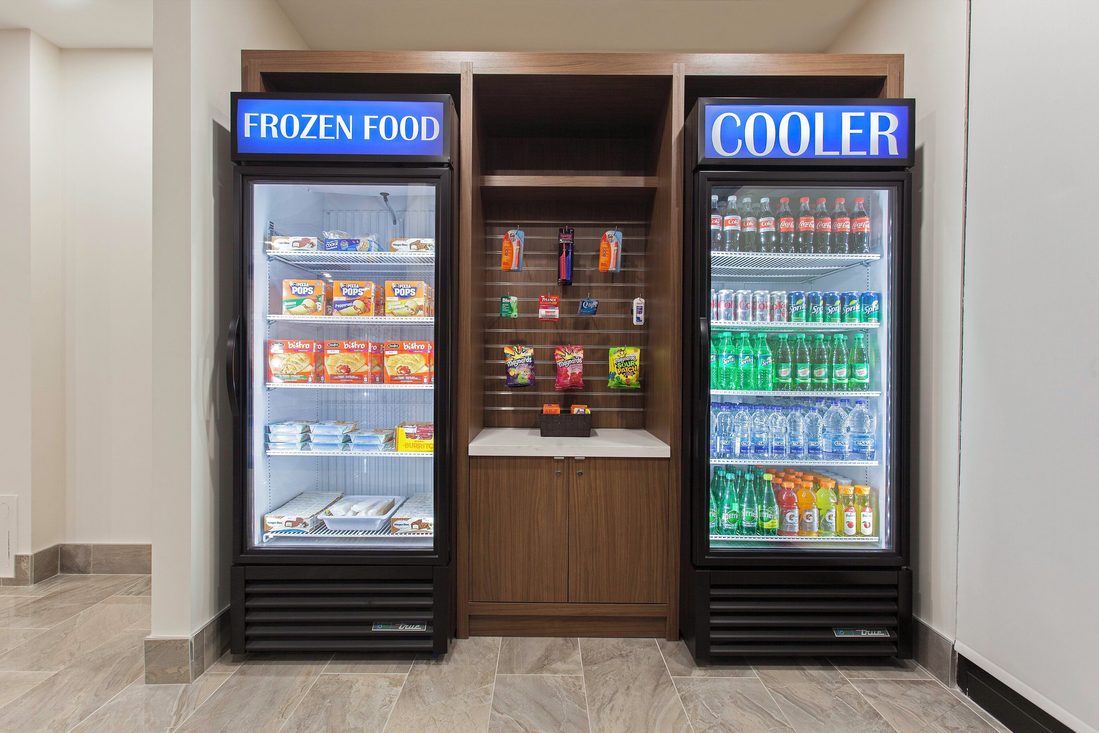 Two refrigerated display cases labeled 'FROZEN FOOD' and 'COOLER' with various food and beverage items inside.