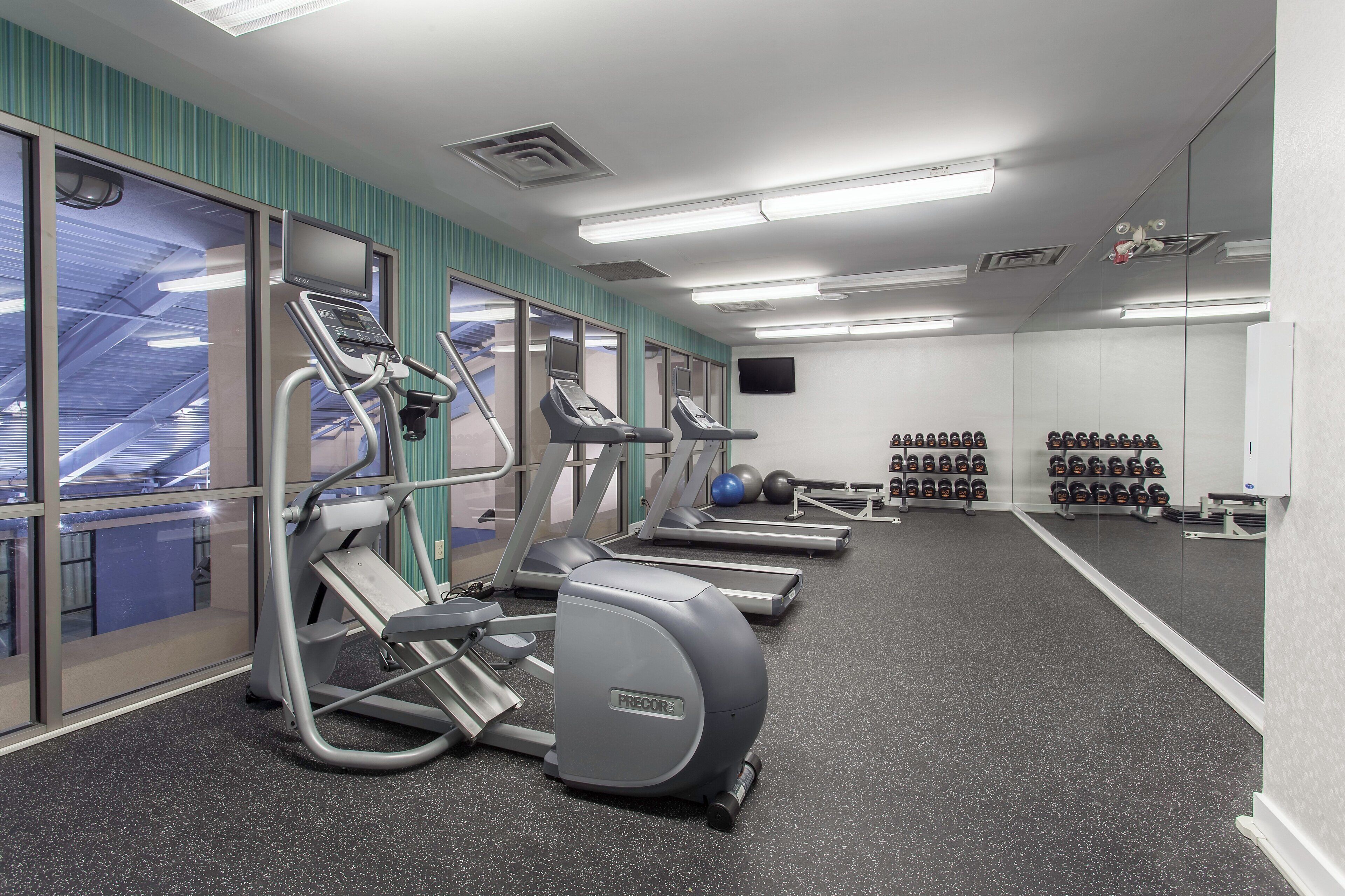 A gym with treadmills, elliptical machines, and weight stations.