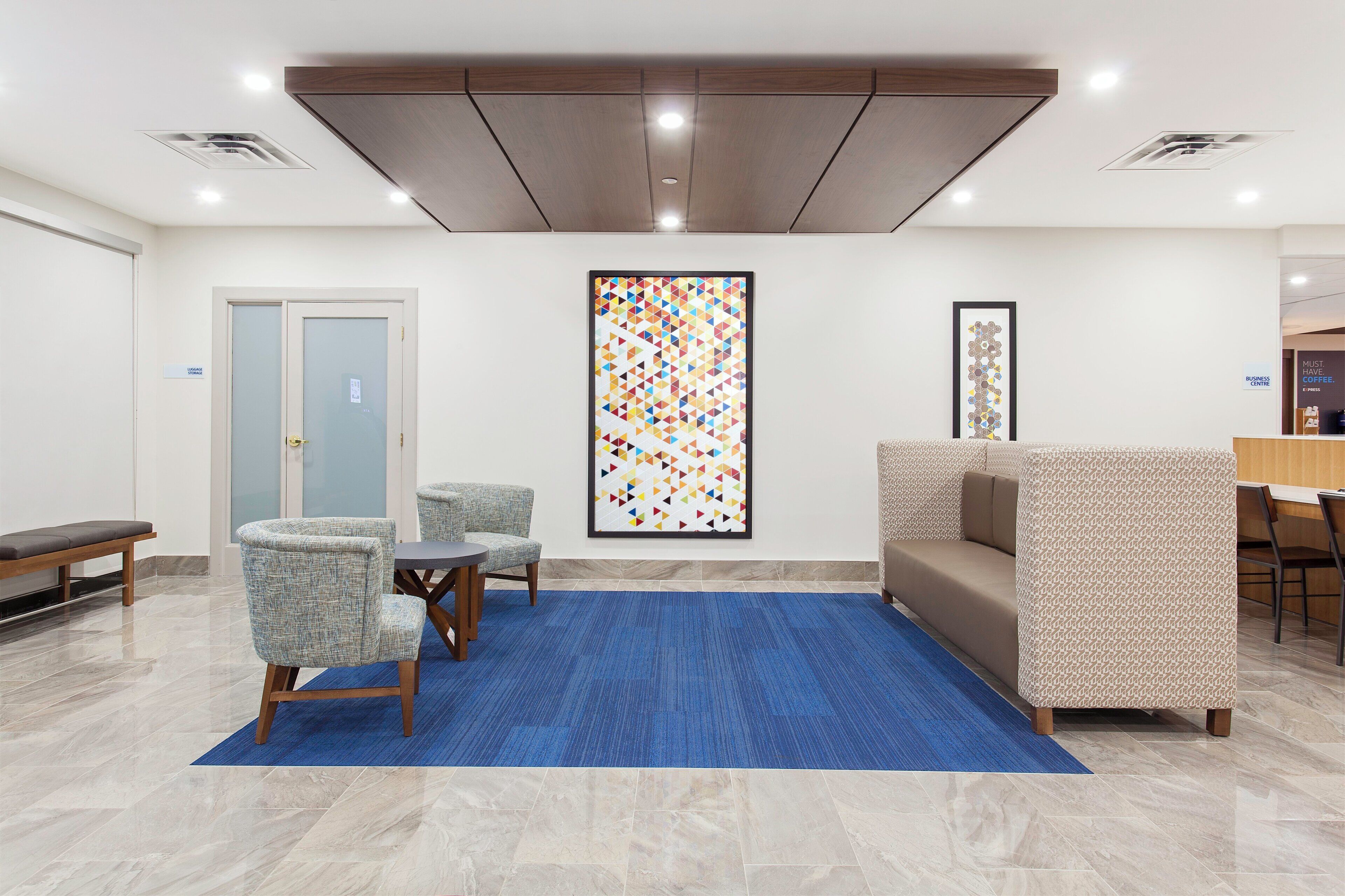 A lobby with a reception desk, seating area, and a large abstract art piece.