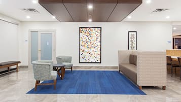 A lobby with a reception desk, seating area, and a large abstract art piece.