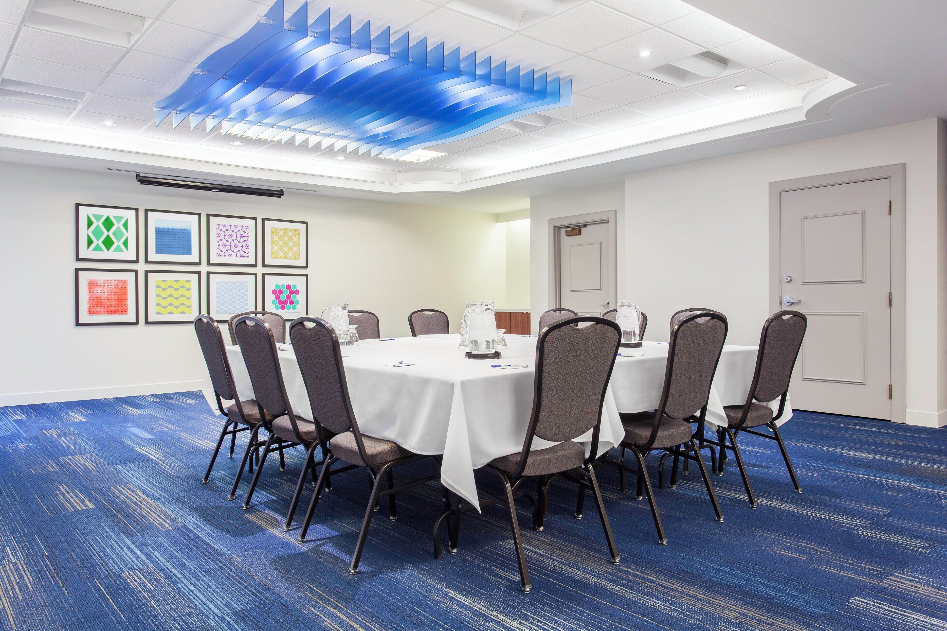 A conference room with a round table, chairs, and a blue carpet.