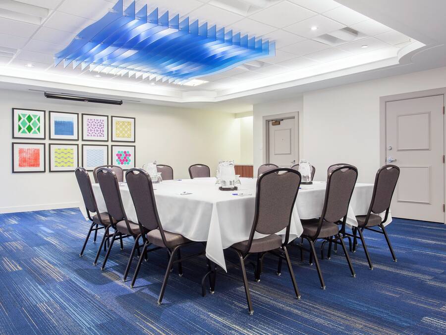 A conference room with a round table, chairs, and a blue carpet.