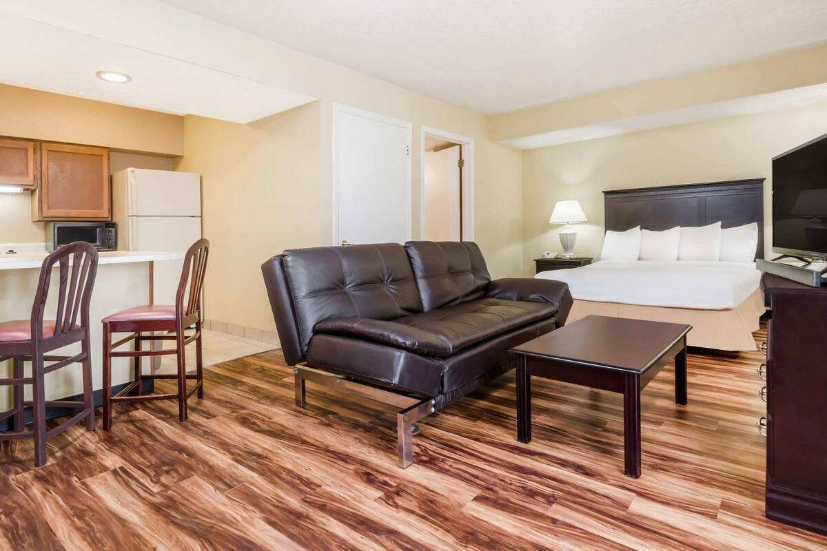 Une chambre d’hôtel équipée d’un canapé, d’un lit, d’un bureau avec une chaise, d’une télévision et d’une lampe.