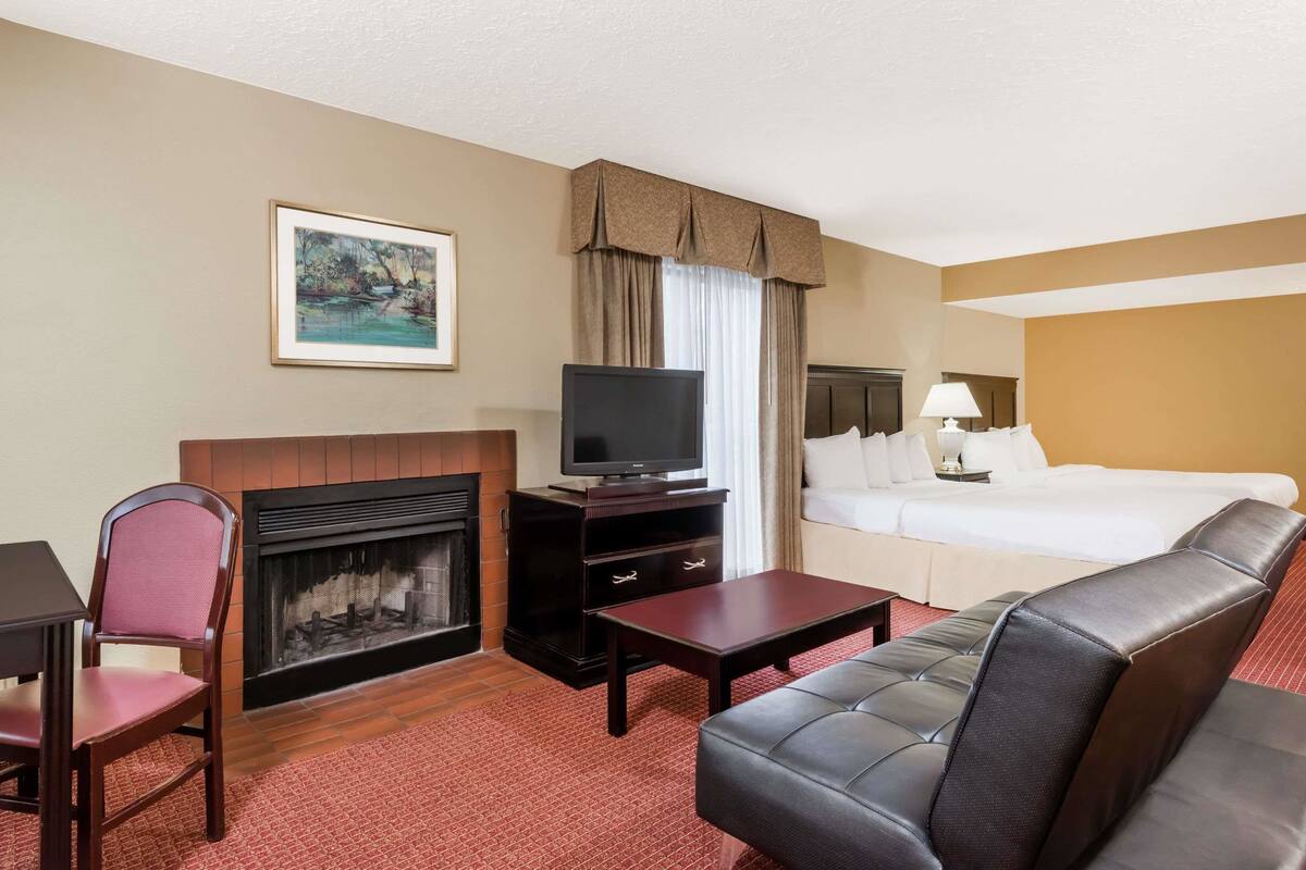 Une chambre d’hôtel équipée d’une cheminée, d’une télévision, d’un lit, d’un canapé et d’un bureau.