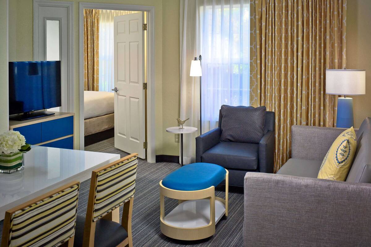 Una habitación de hotel con cama, televisión, sofá, una mesita y una silla.