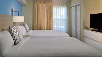A hotel room with two beds, a television, a lamp, and a window with curtains.