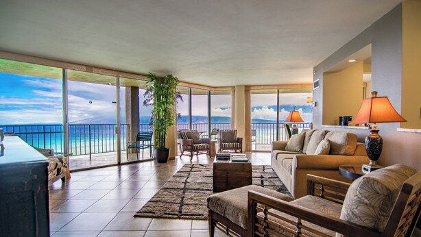 A spacious living room with a large window overlooking the ocean, furnished with a sofa, chairs, and a coffee table. - Royal Kahana Maui by OUTRIGGER (Lahaina)