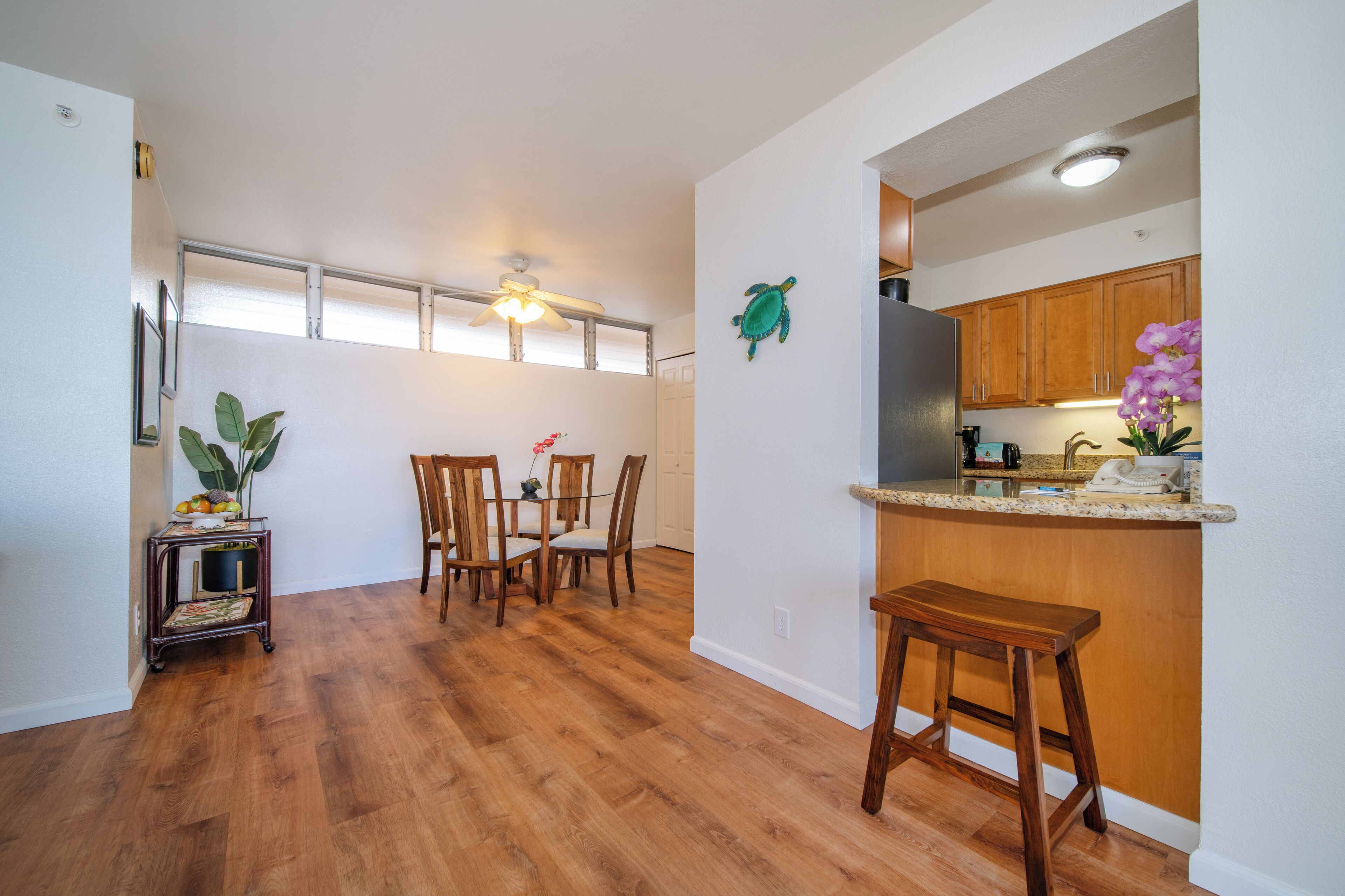 A spacious kitchen with wooden cabinets, a dining area with a table and chairs, and a small bar stool.