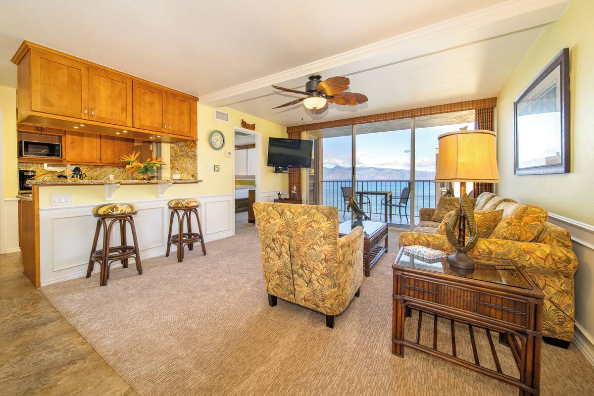 A spacious living area with a kitchen, a dining area, and a balcony with a view.