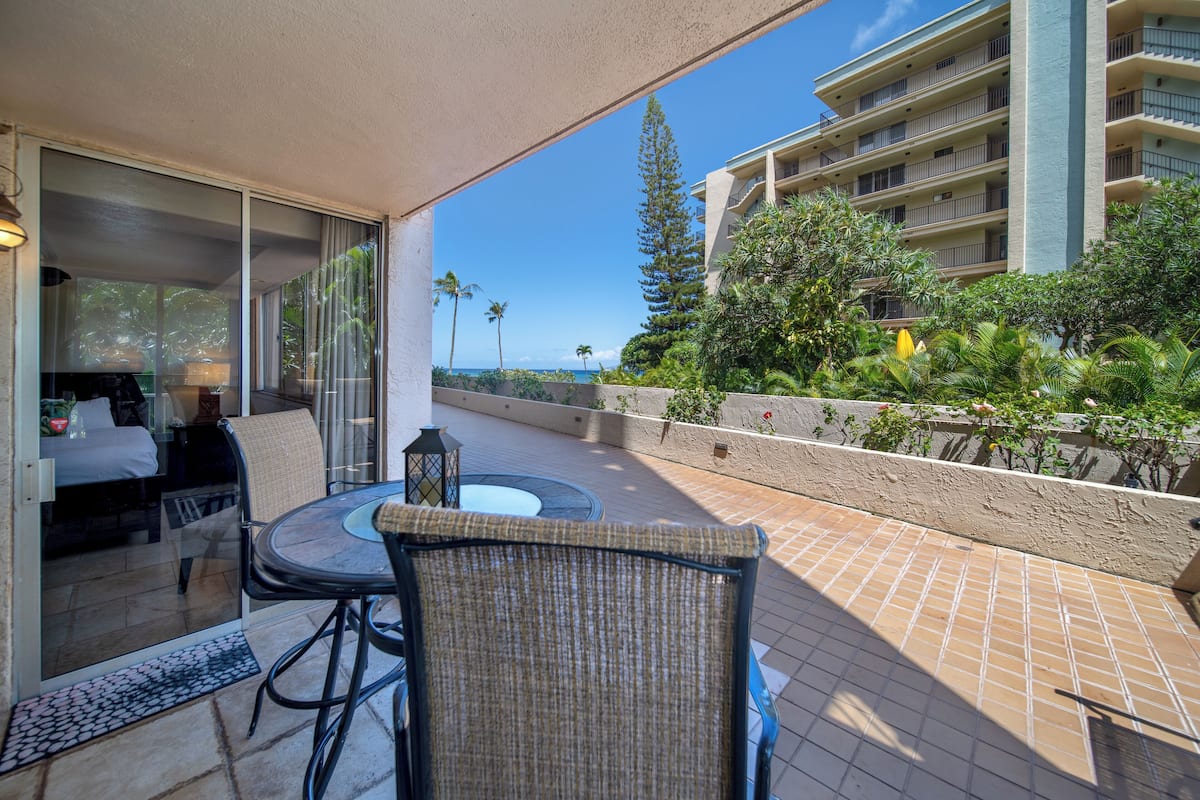 An outdoor patio with a table and chairs, a view of a building, and a clear sky.