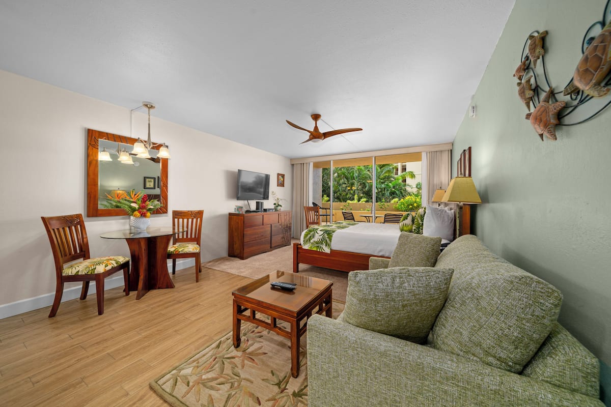 A living room with a sofa, chairs, a coffee table, a TV, and a ceiling fan.