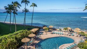 A resort pool area with clear blue water, surrounded by lounge chairs and umbrellas, overlooking the ocean. - Royal Kahana Maui by OUTRIGGER (Lahaina)