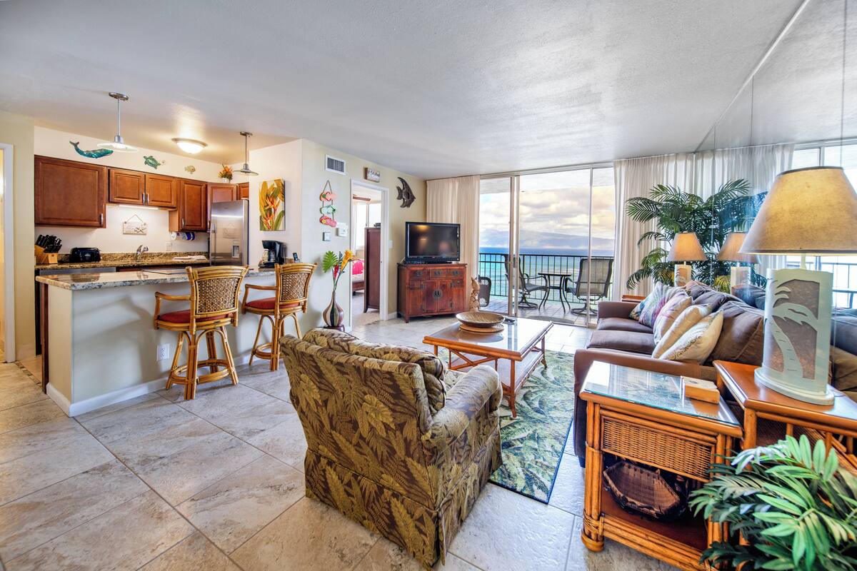 A spacious living area with a kitchen, dining area, and a balcony with a view.