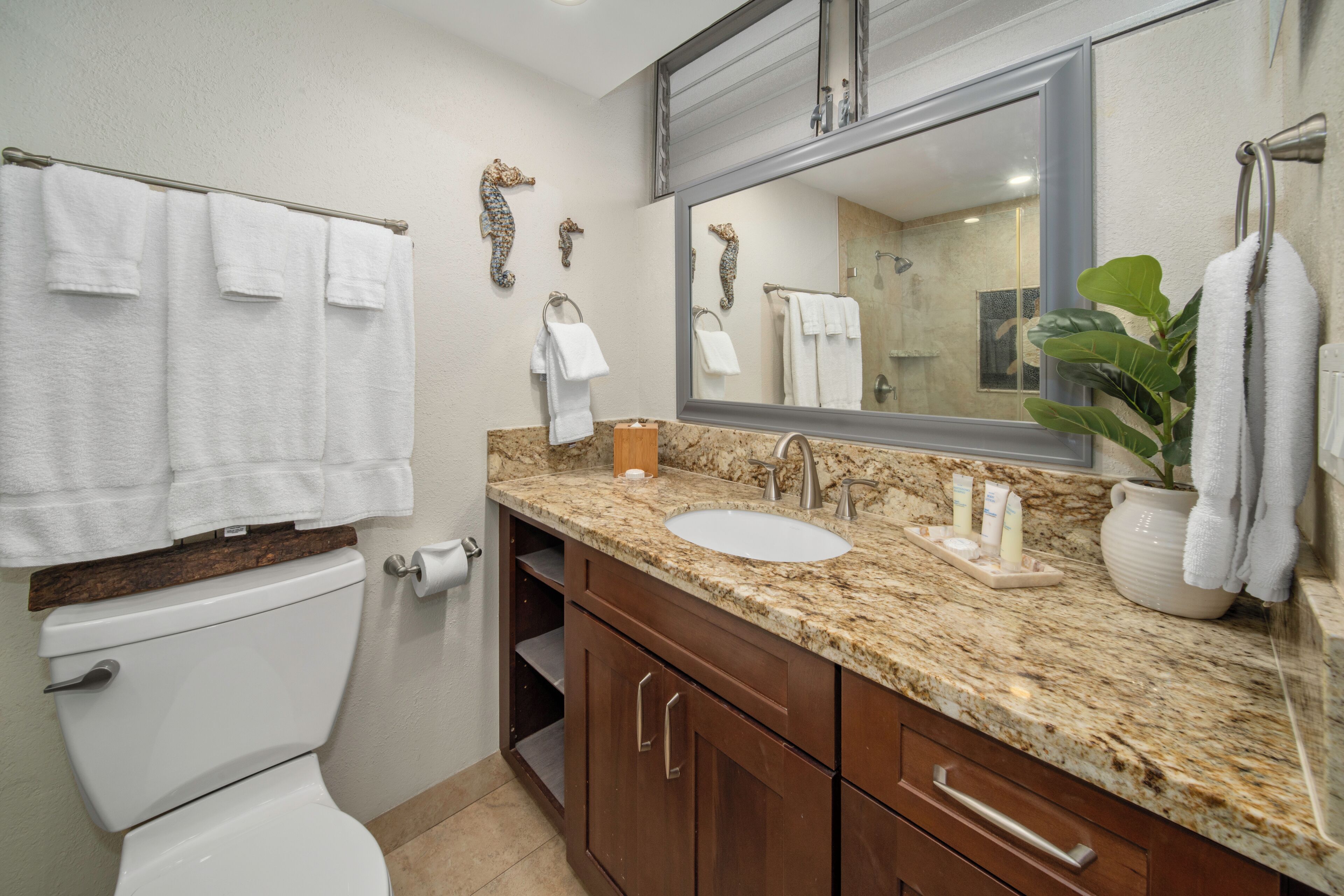 A bathroom with a toilet, sink, vanity, and towel rack.