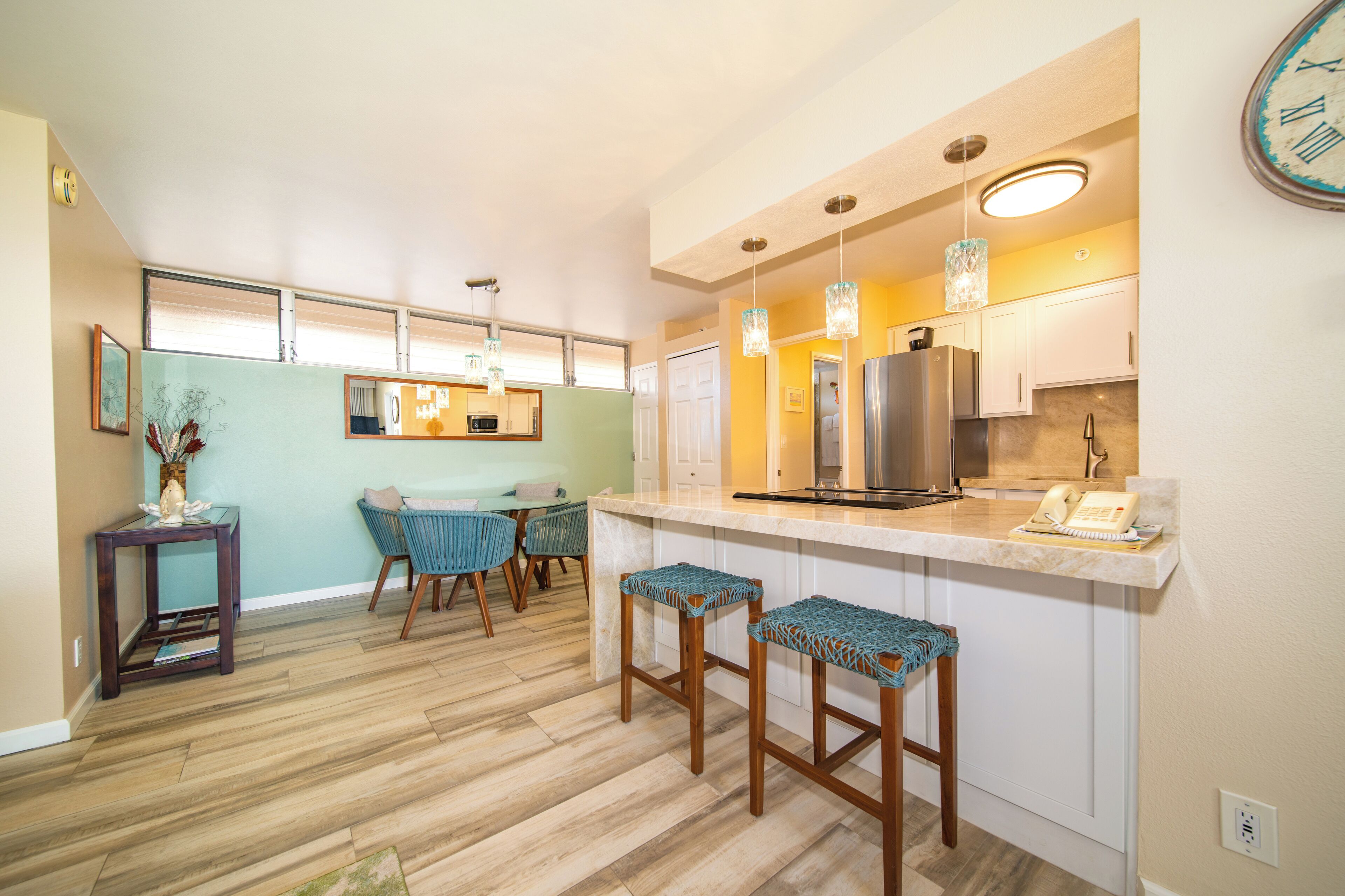 Una cocina moderna con una isla central, taburetes de bar y un comedor con mesa y sillas.