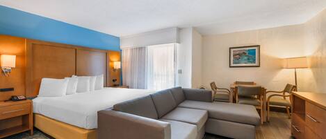 A hotel room with a large bed, a sofa, a desk, and a chair.