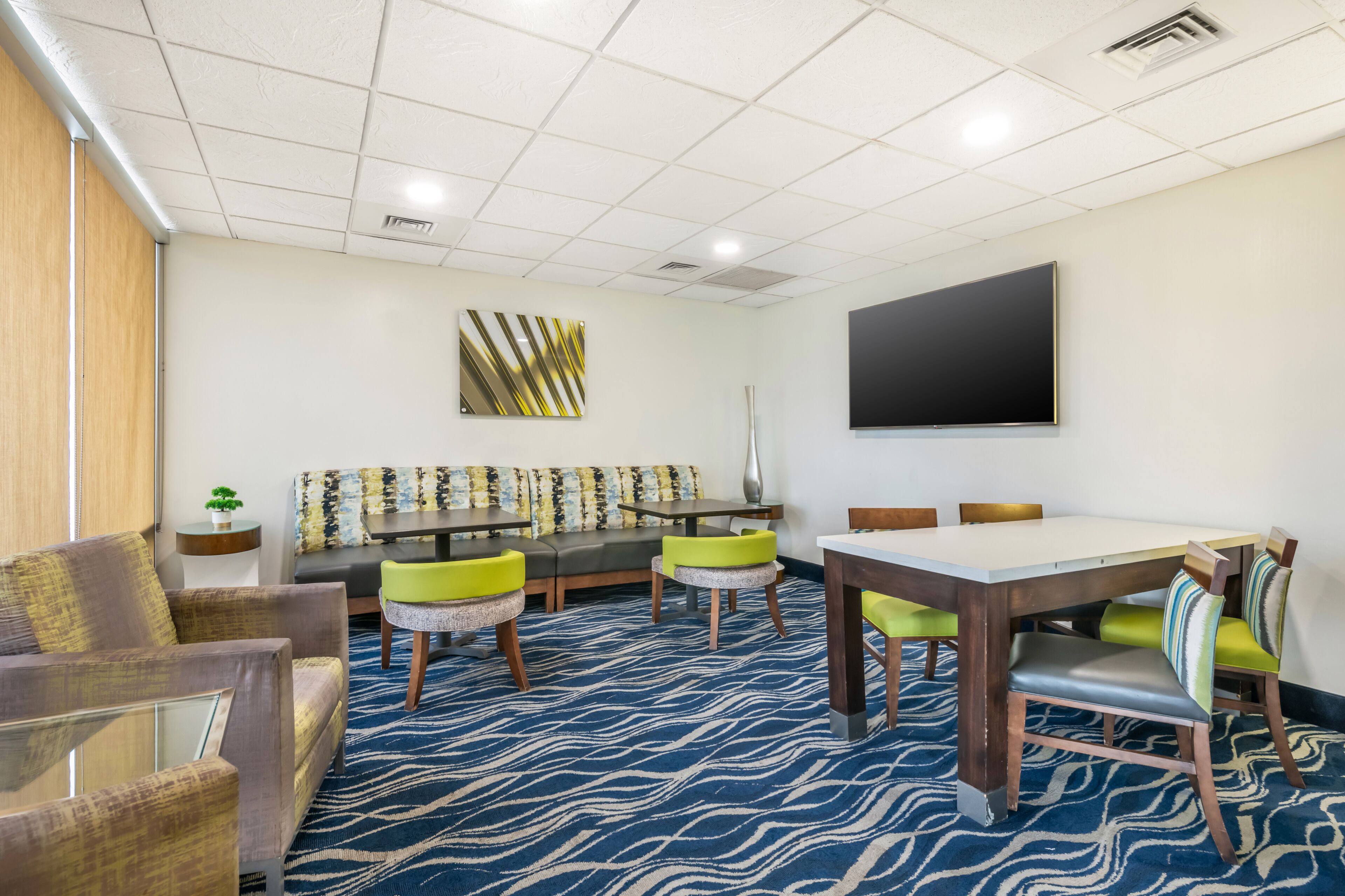 A conference room with a large table, chairs, a sofa, and a television.