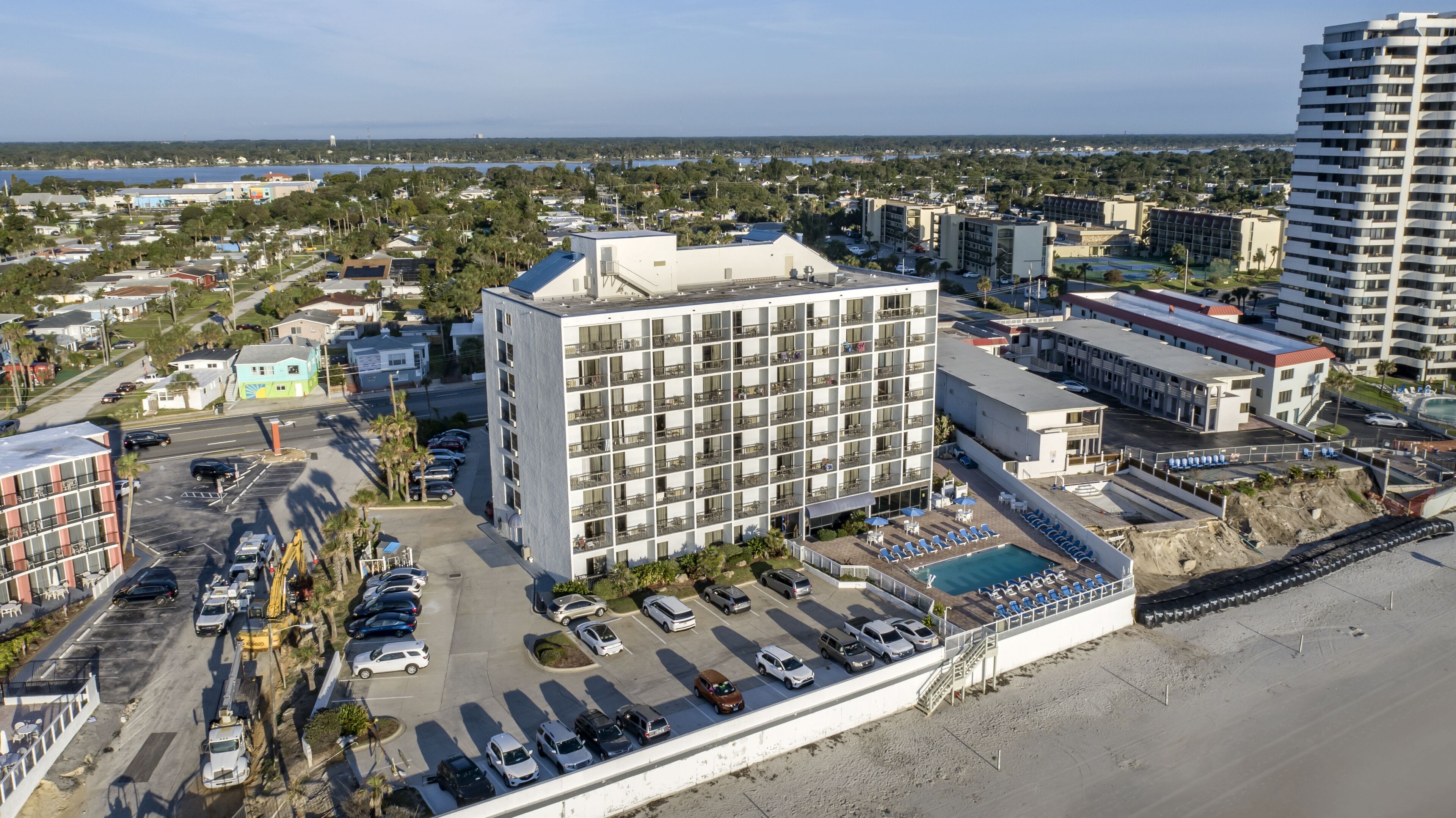 A multi-story hotel with a central courtyard, a pool, and a beachside location.