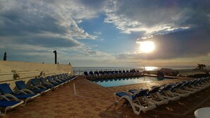 A poolside area with lounge chairs and a view of the ocean. - Tropical Winds Oceanfront Hotel (Daytona Beach)