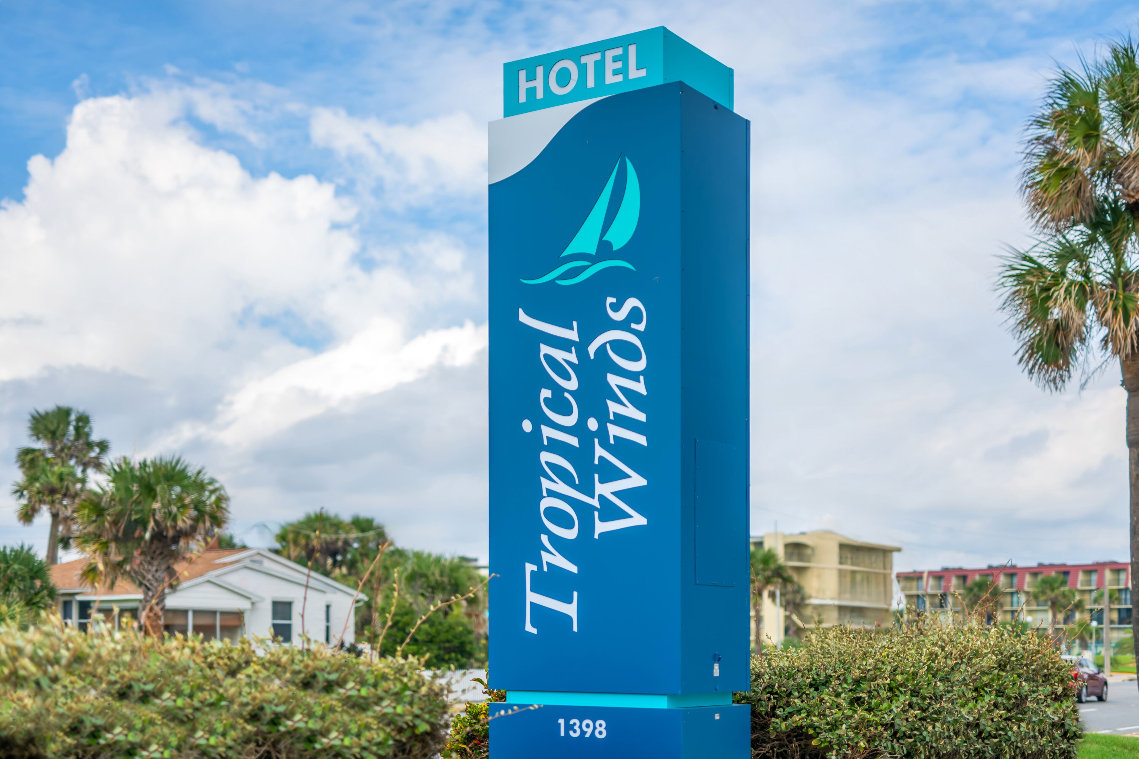A hotel sign with the name "Tropical Winds" and the number "1398".